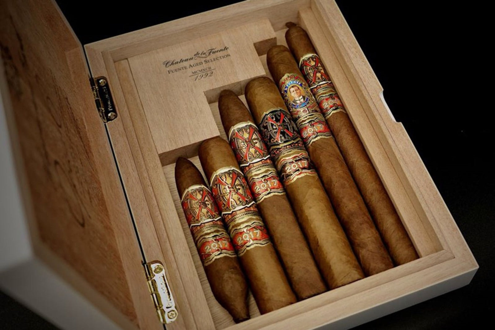 Arturo Fuente Opus X cigars arranged in an open cedar box against a dark backdrop