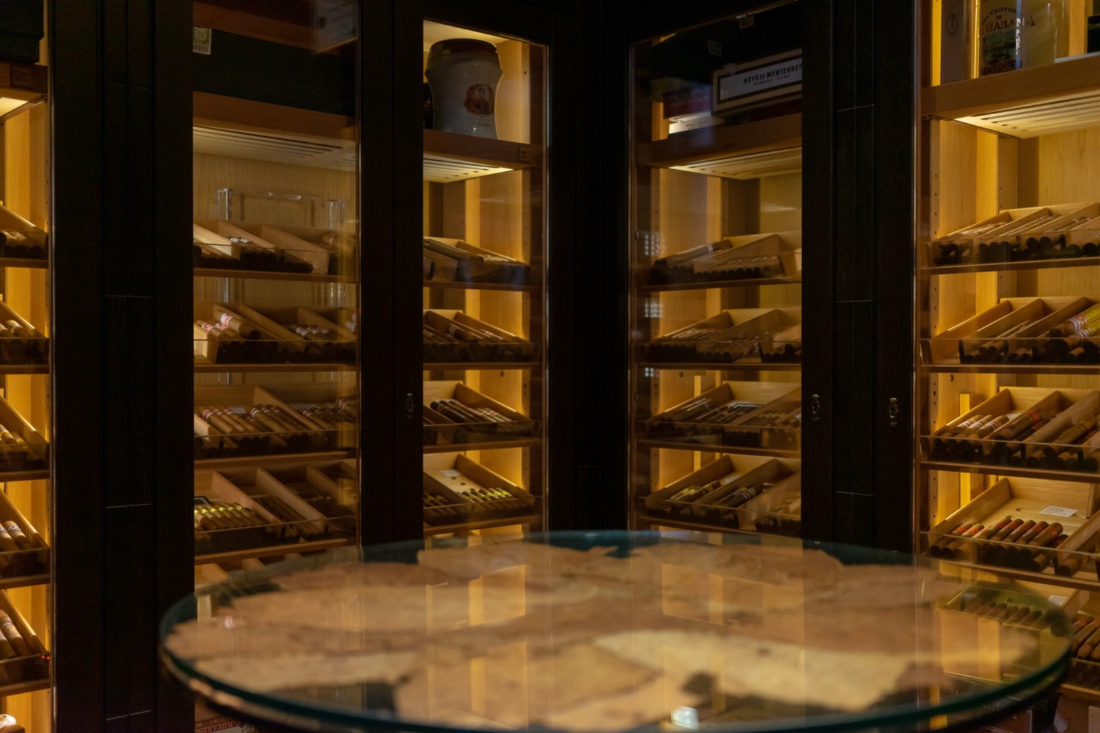 Luxury cigar lounge humidor room with illuminated cabinets of premium cigars, the perfect setting for a long evening smoke