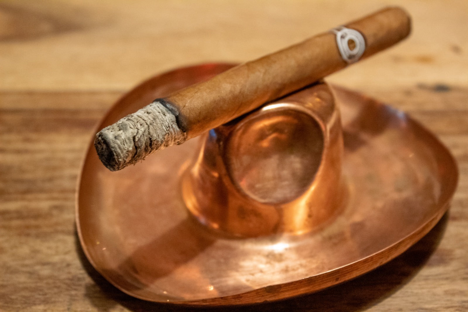 Lit Montecristo Especial No 2, one of the best Montecristo cigars, resting with a solid ash on a copper ashtray