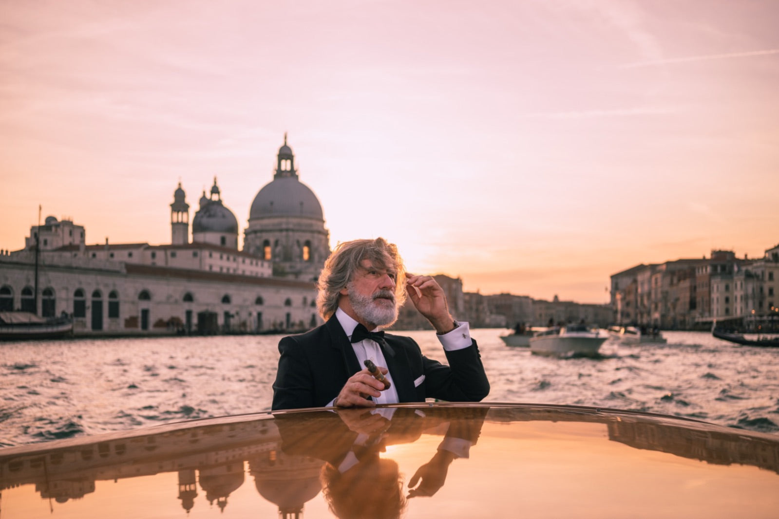 Gentleman enjoying one of the best summer cigars in a Venetian water taxi at golden-hour sunset on the Grand Canal