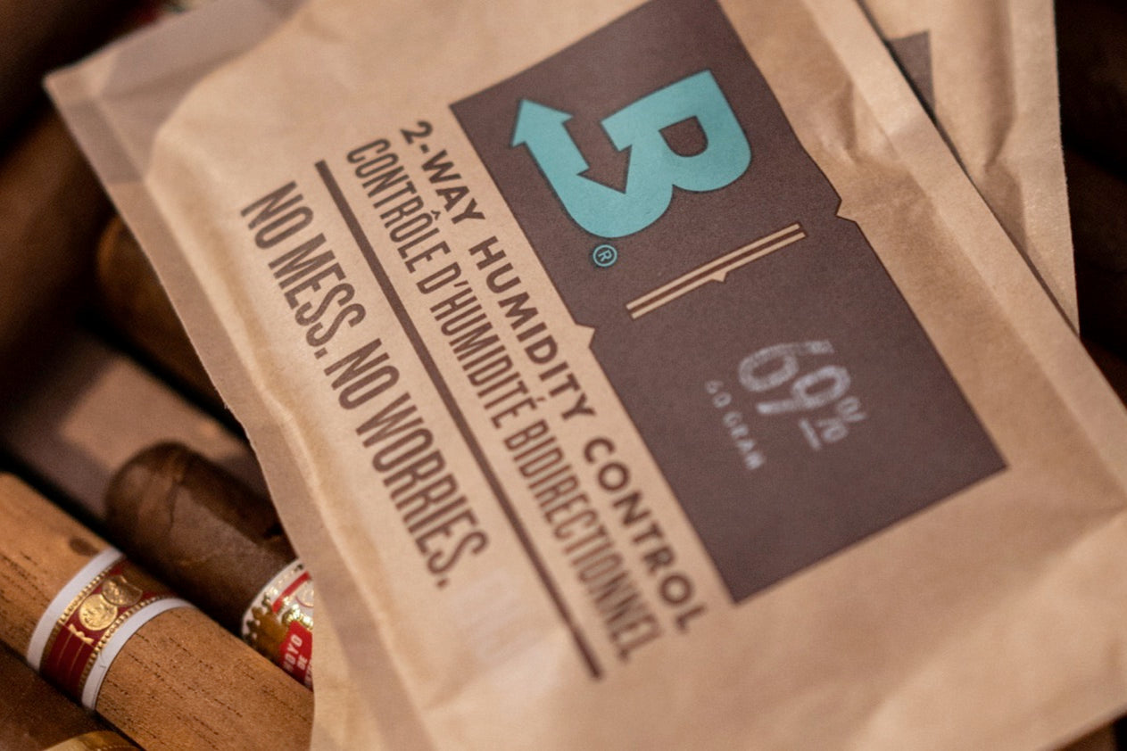 Boveda 2-way humidity control pack resting on premium cigars to keep cigars fresh and prevent them from expiring