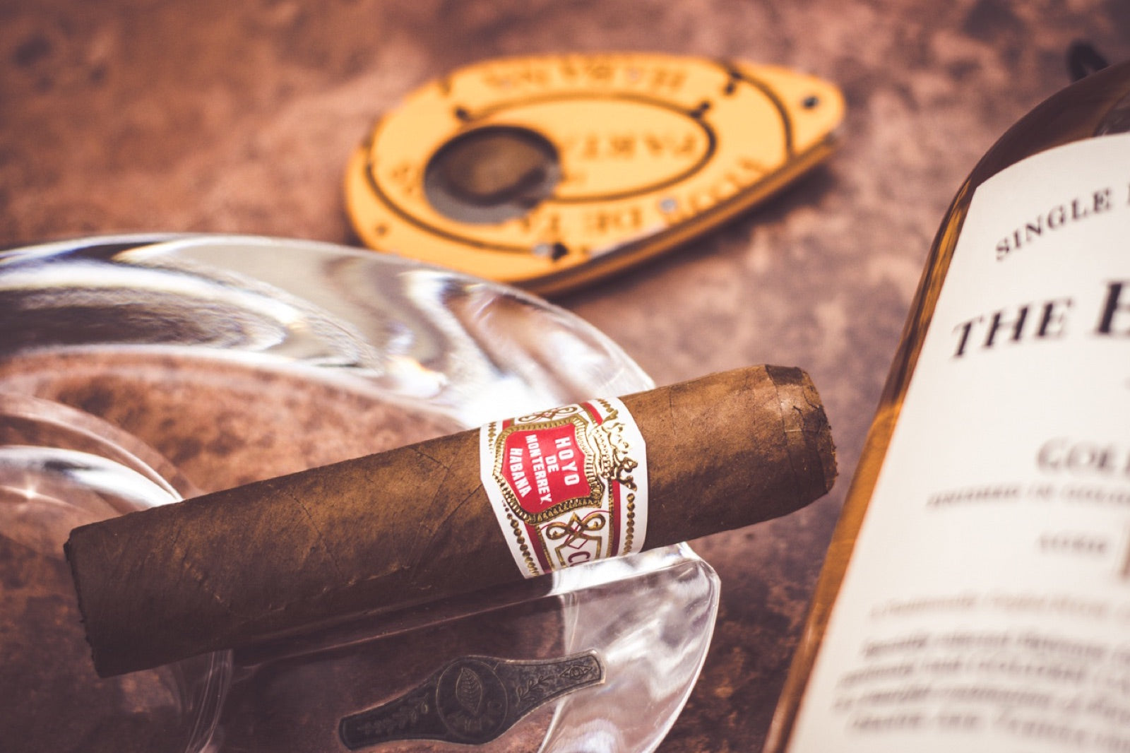 Premium Hoyo de Monterrey robusto resting on a crystal ashtray beside a single malt whisky, illustrating cigar sizes, vitolas and ring gauge