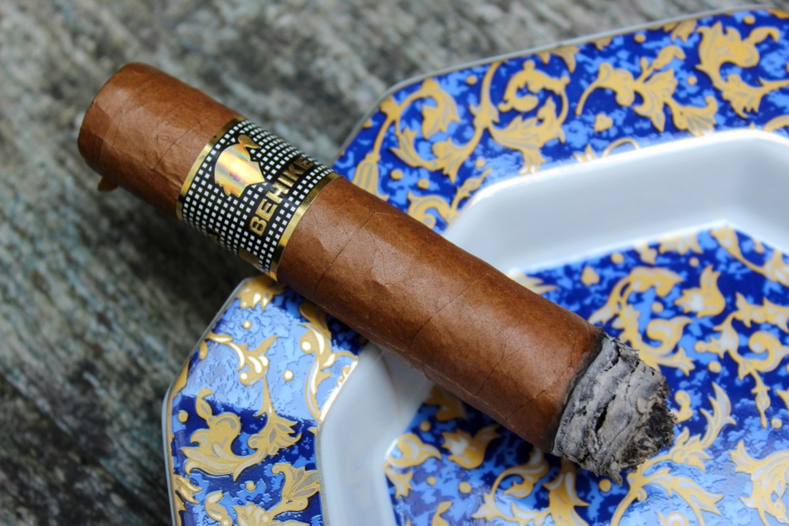 Cohiba Behike 56 Cuban cigar resting on a copper ashtray, the prestige side of Cohiba vs Montecristo