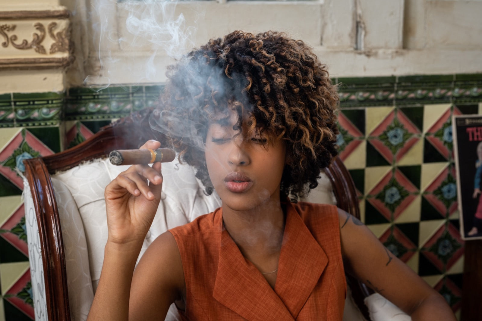 Woman savouring a hand-rolled double corona cigar in an atmospheric tiled Havana interior with swirling smoke