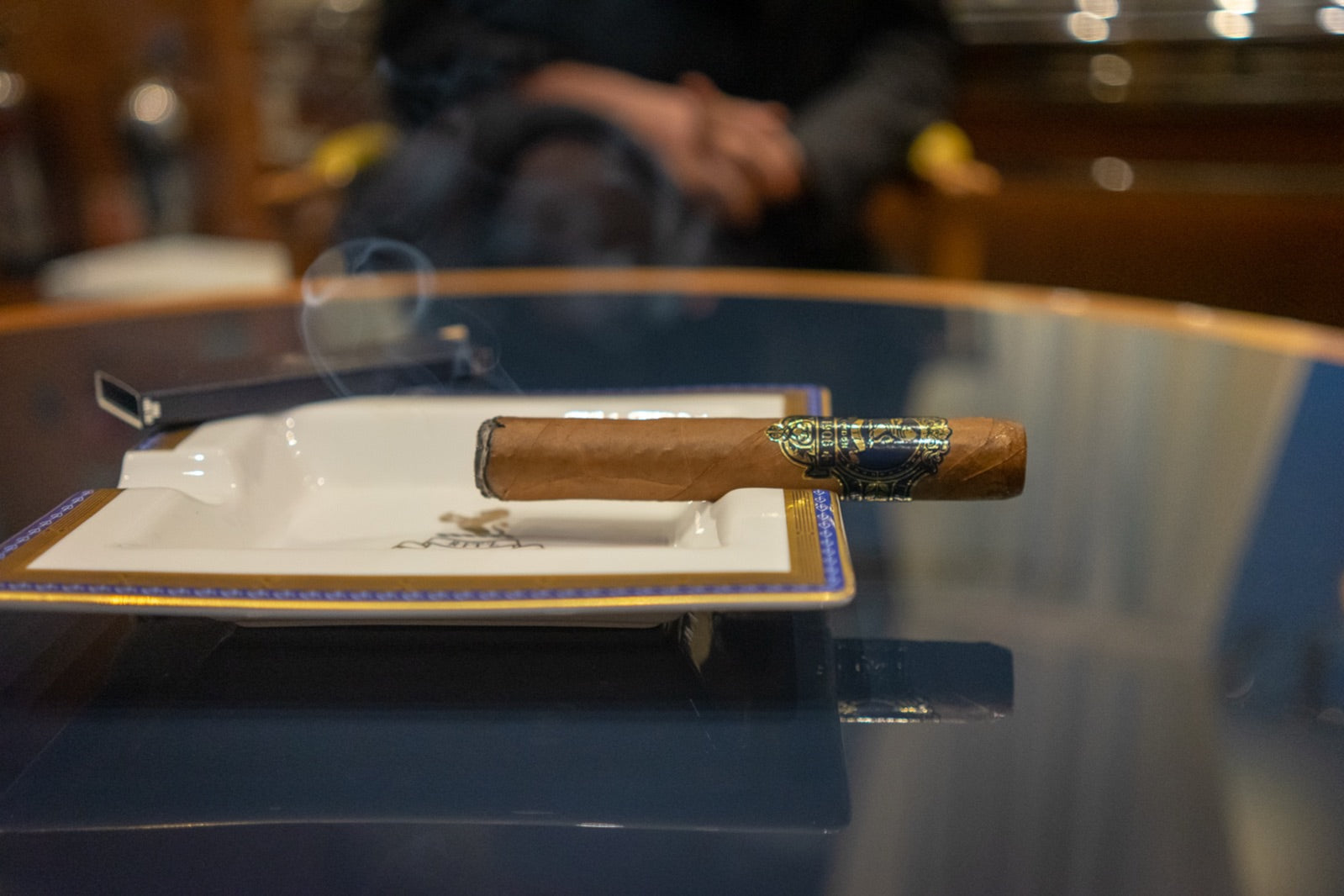 Lit premium Cuban cigar resting on a Cohiba ashtray with curling smoke in a dark luxury lounge, a moment to celebrate a promotion