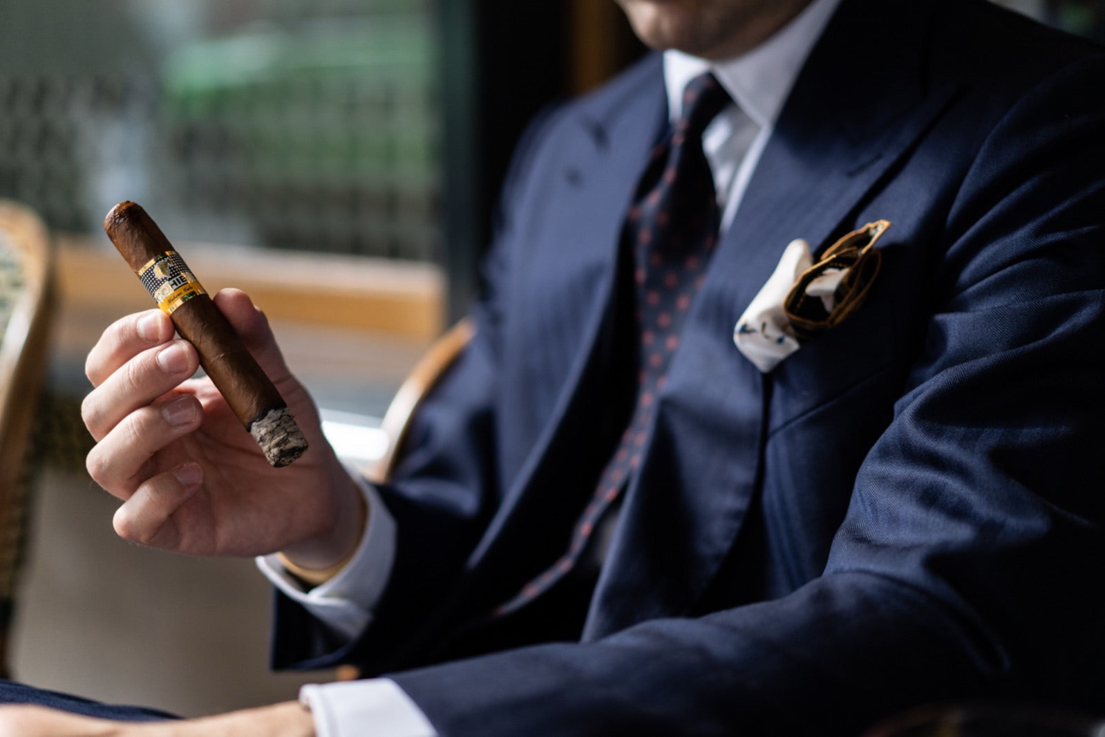 Well-dressed gentleman in a navy suit relaxing with a premium cigar, one of the best cigars for beginners in an elegant lounge