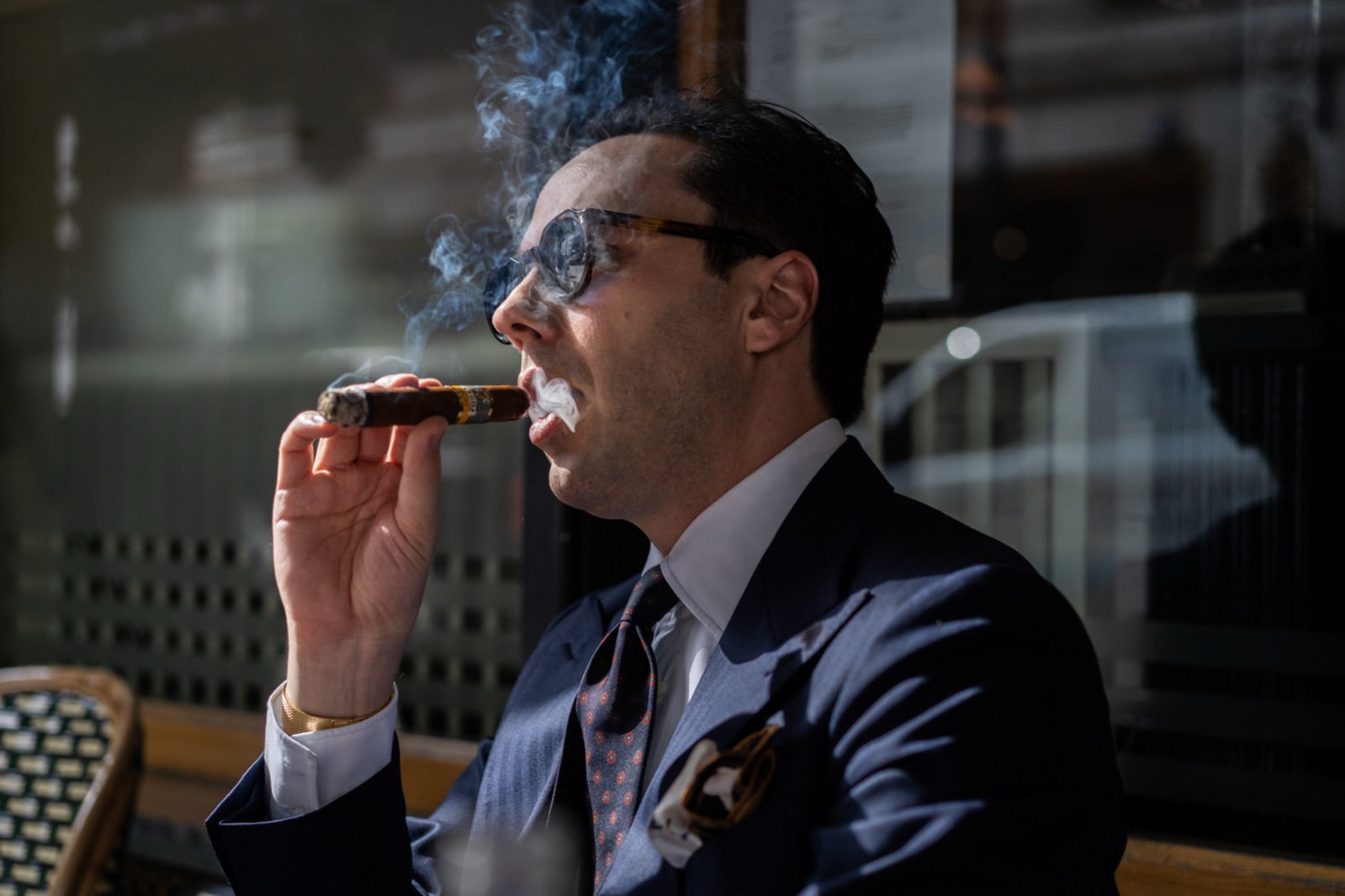 Well-dressed gentleman savoring one of the best cigars to celebrate a new baby in an elegant lounge