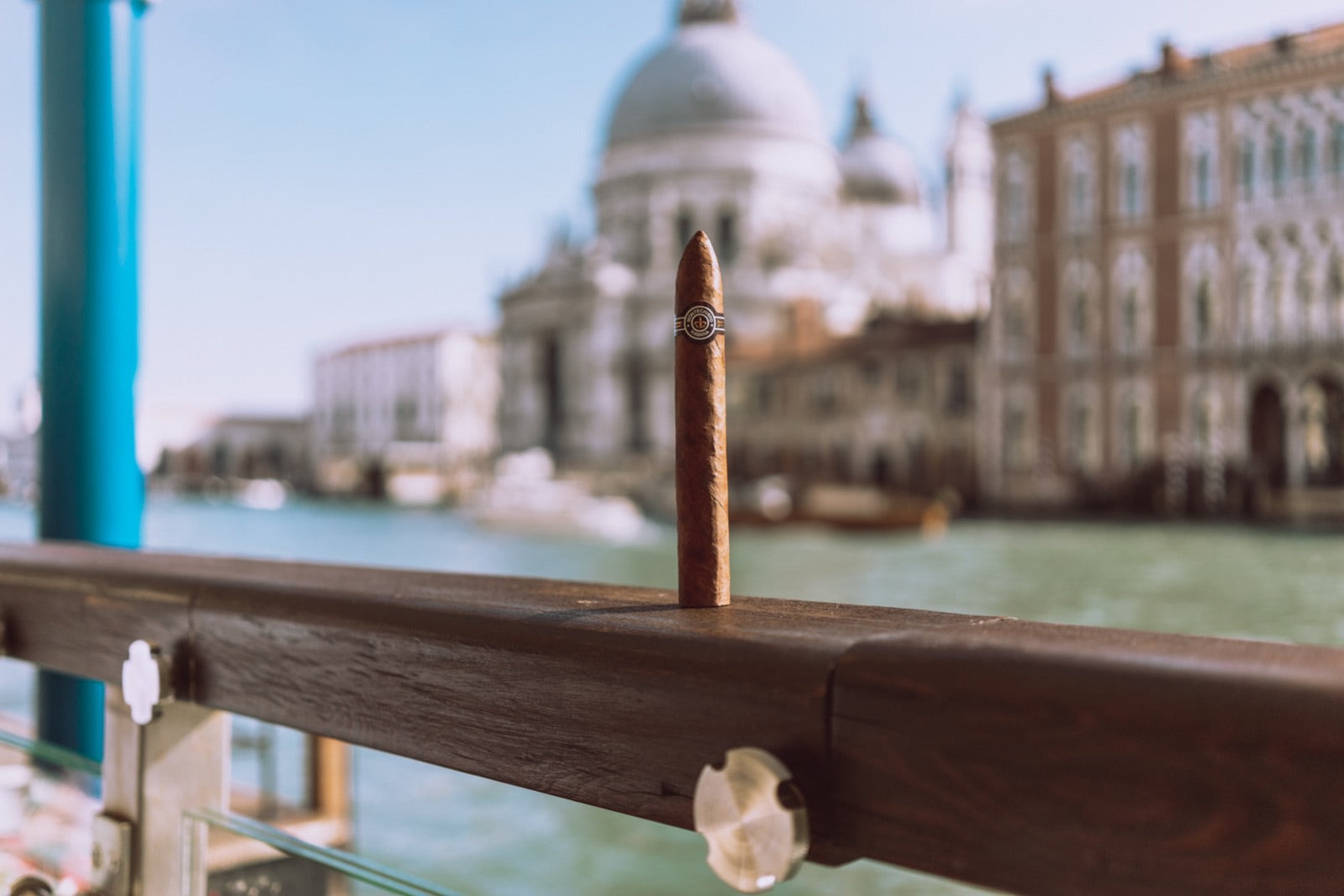 Premium cigar standing on a wooden railing above the Venice Grand Canal, one of the best cigars to take on holiday