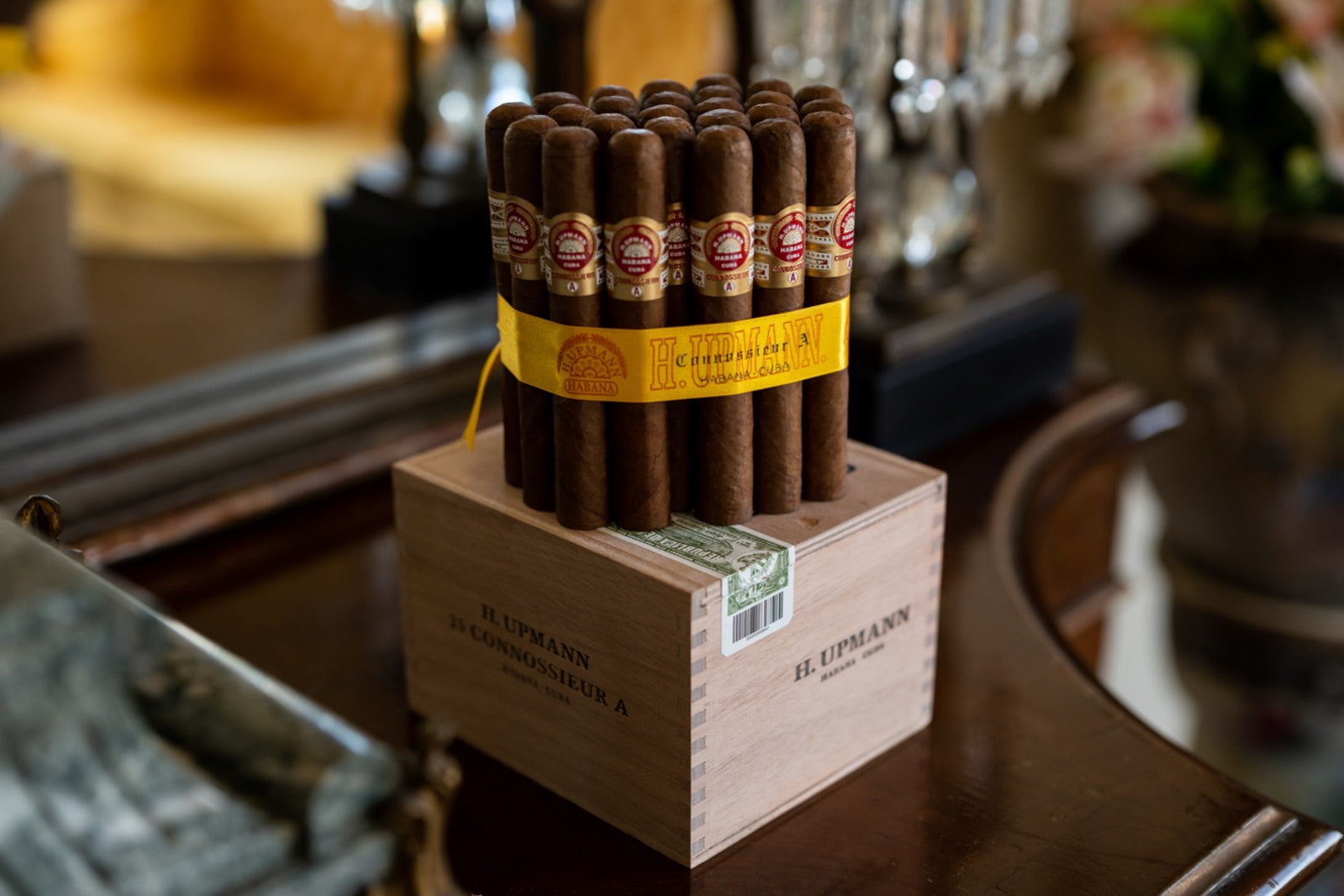 Bundle of premium Cuban cigars resting on a wooden H. Upmann box in a warm luxury lounge, best limited edition Cuban cigars