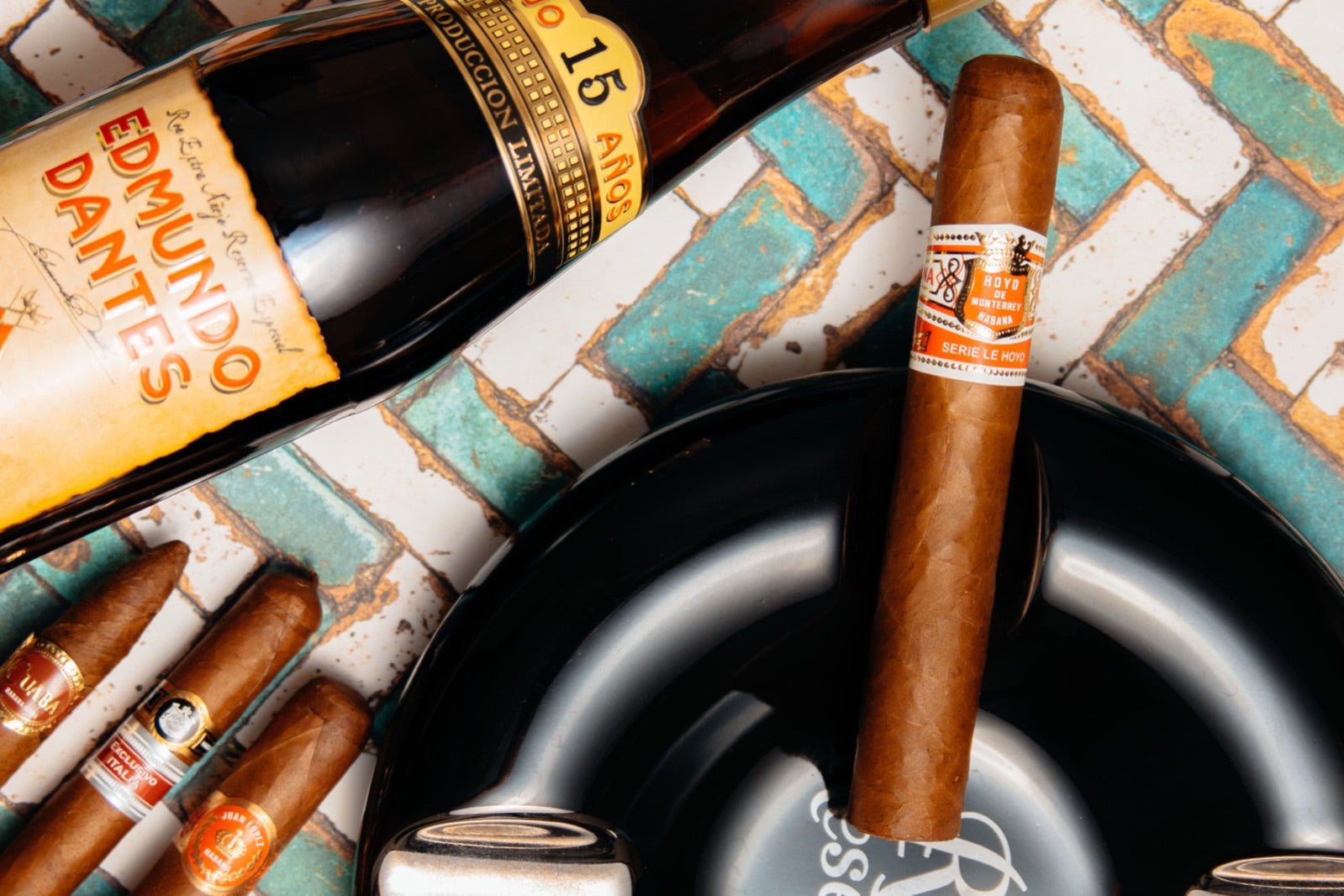 Premium cigar standing in a black ashtray beside aged rum and a row of cigars, choosing your first premium cigar