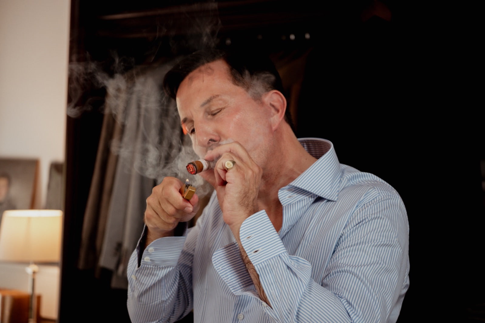 Man lighting a premium Plasencia cigar with swirling smoke, evoking five generations of tobacco craft