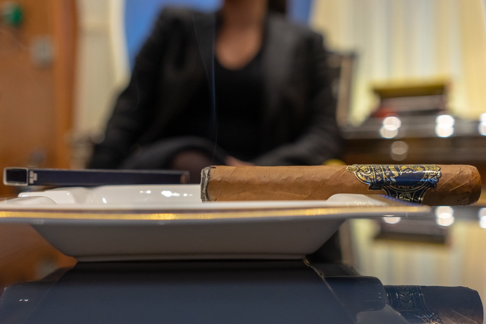 Lit premium cigar resting on a white ashtray in an elegant lounge, ideal for a cigars and port pairing