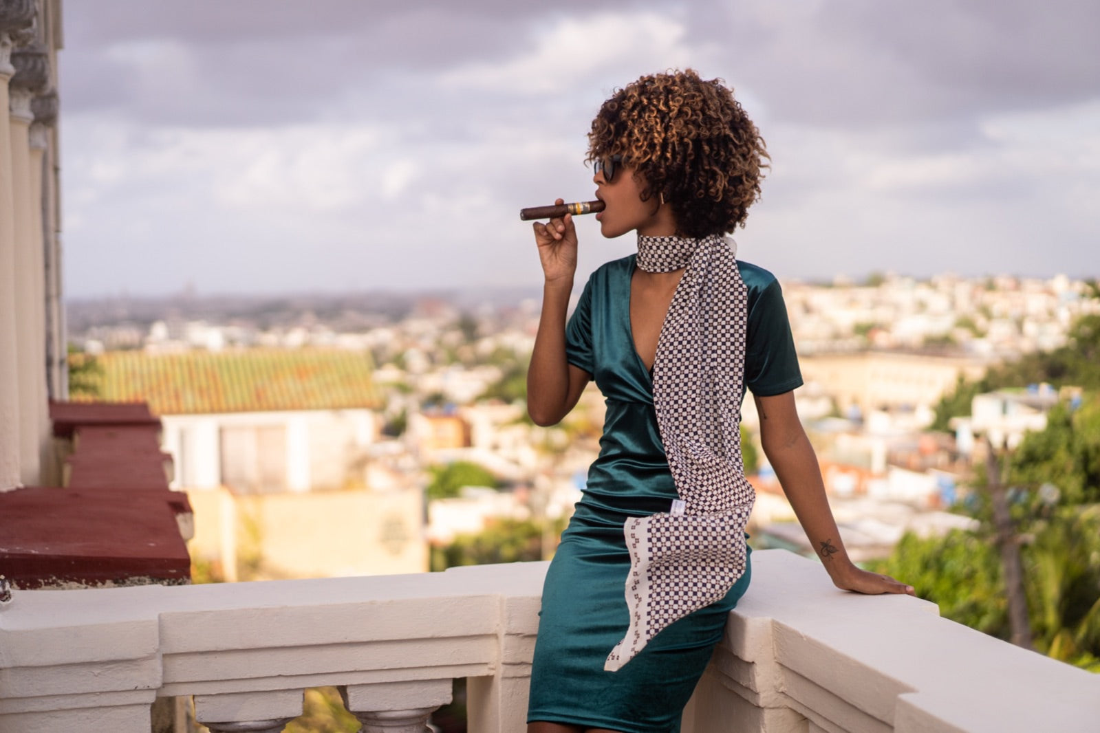Woman smoking a premium Ramon Allones Cuban cigar on a balcony overlooking the Havana skyline