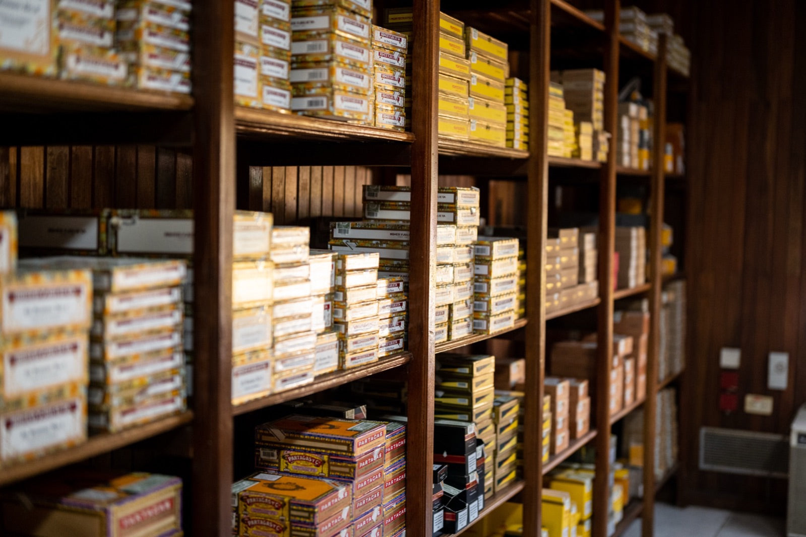 Wooden shelves stacked with cigar boxes in a humidor storage room, ideal conditions after seasoning a new humidor